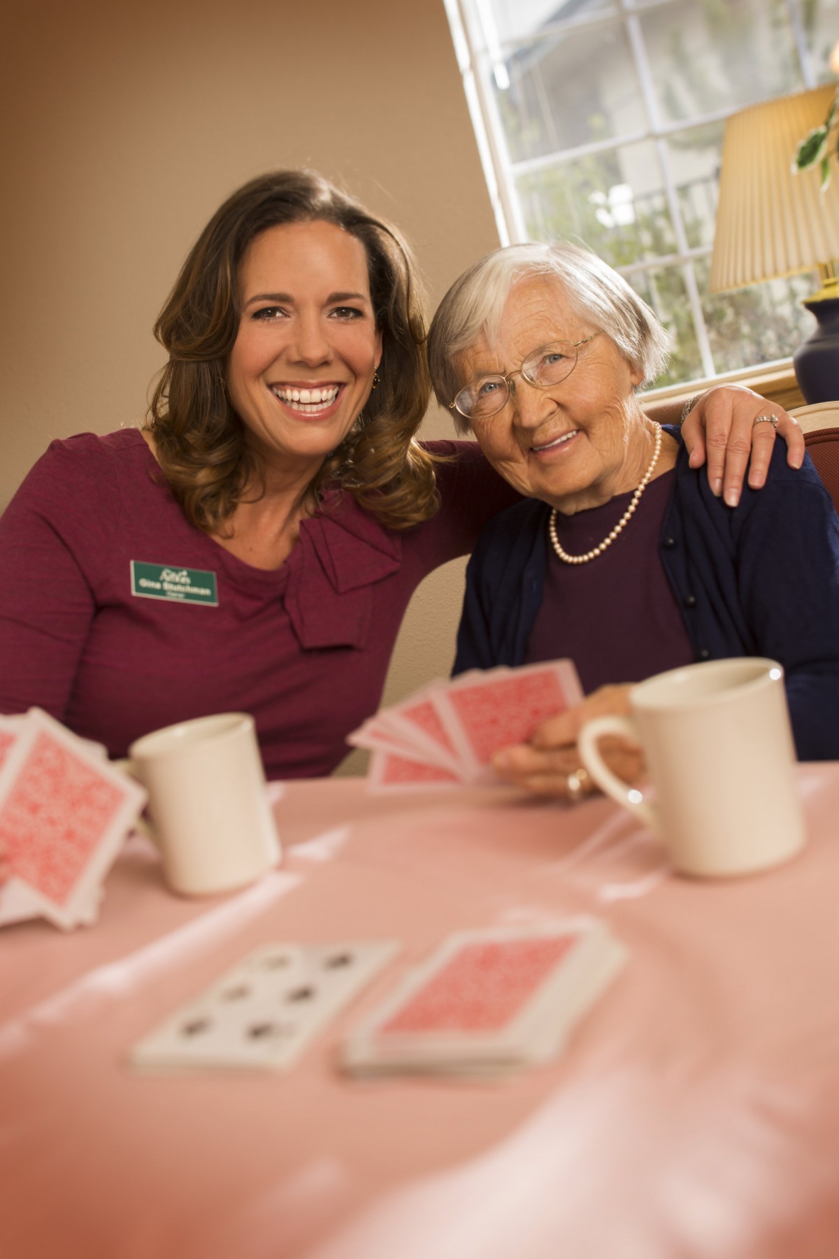 Two women enjoying a game of cards together indoors, sharing smiles and companionship.