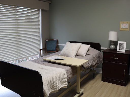 A well-lit hospital room featuring a single bed with comfortable bedding and a nightstand.