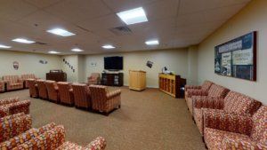 A conference room with comfortable seating, a television, and a podium.
