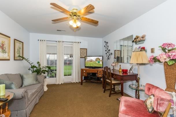 A cozy living room with a ceiling fan, television, and comfortable furniture.