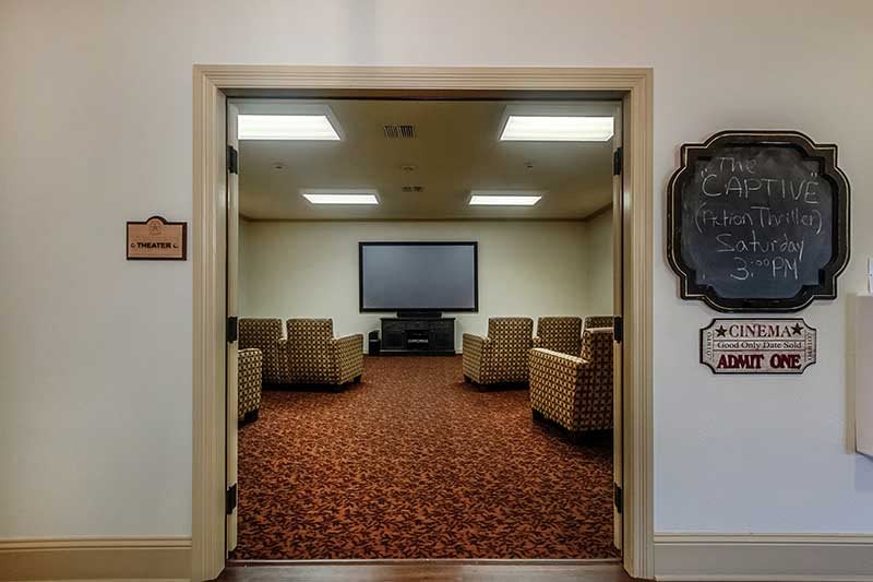 A meeting room with comfortable chairs arranged in front of a large television.