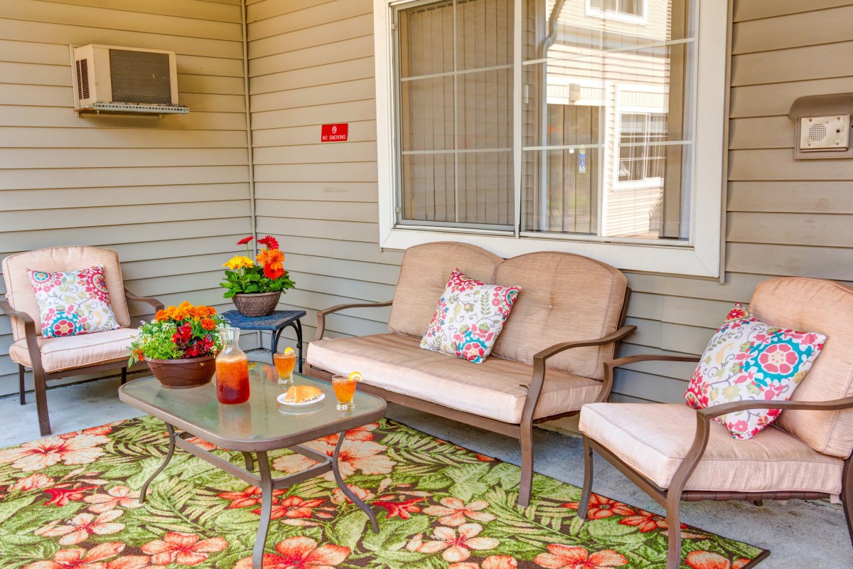 A cozy patio space with comfortable seating, colorful plants, and refreshing drinks on the table.
