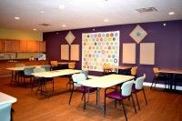 A classroom setting with tables and chairs, featuring a purple accent wall.