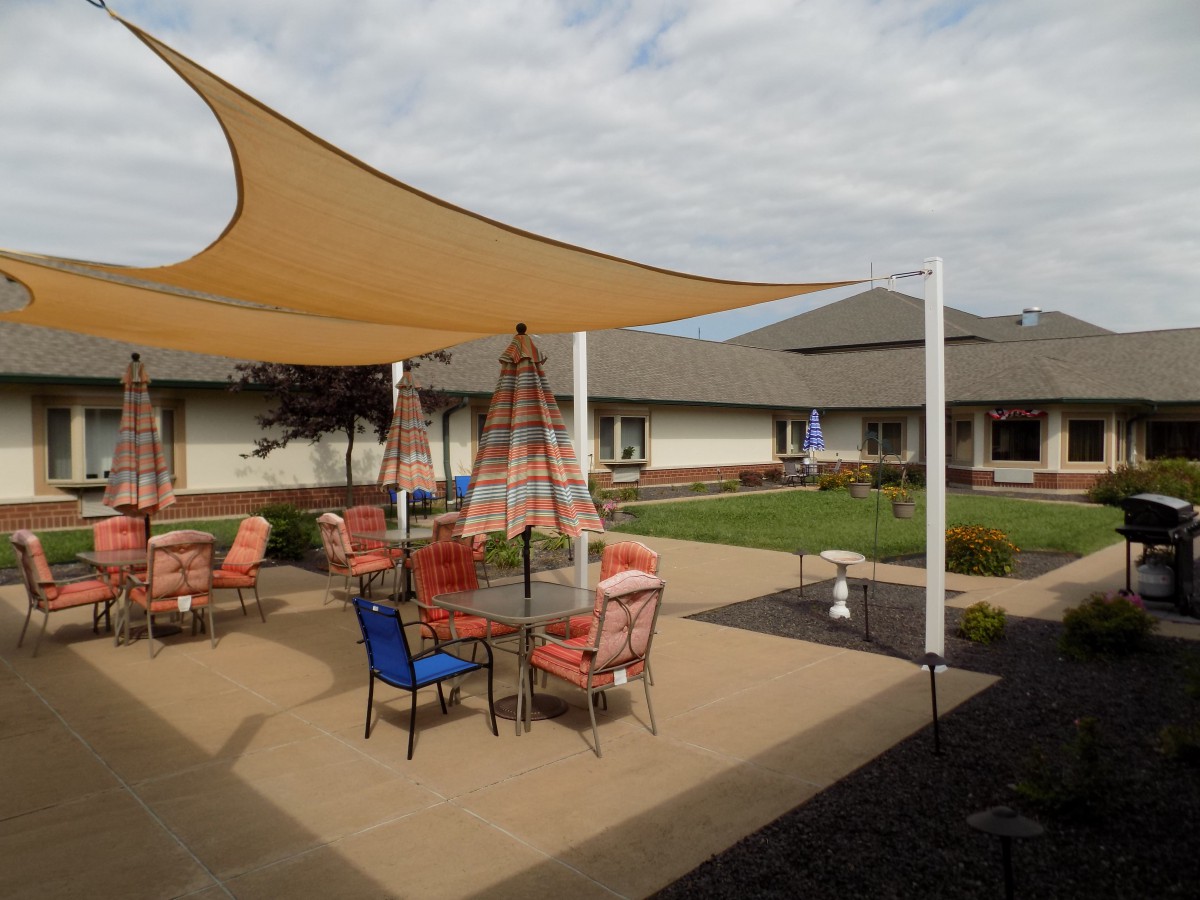 A courtyard patio featuring a shade sail and outdoor furniture.