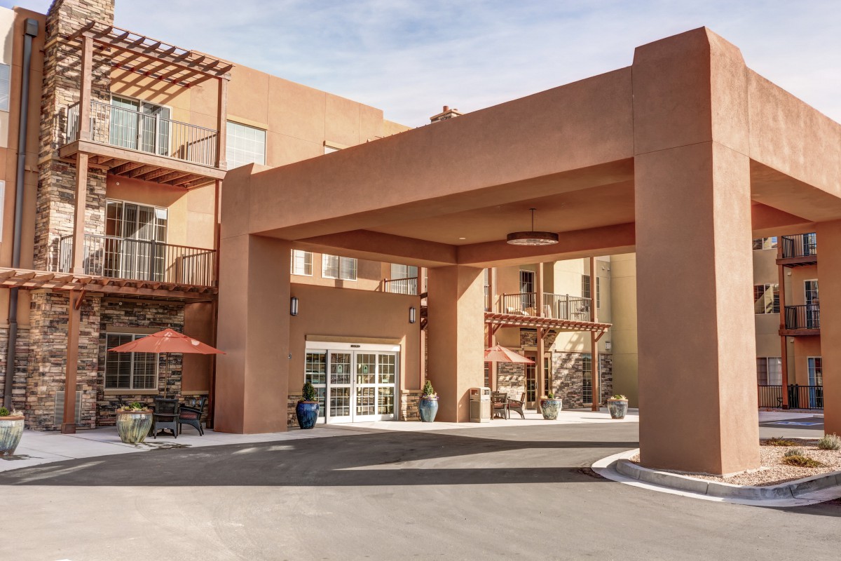 A hotel entrance with southwestern architectural design and a driveway.