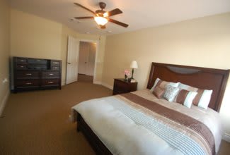 A cozy bedroom with a large bed, wooden furniture, and a ceiling fan.