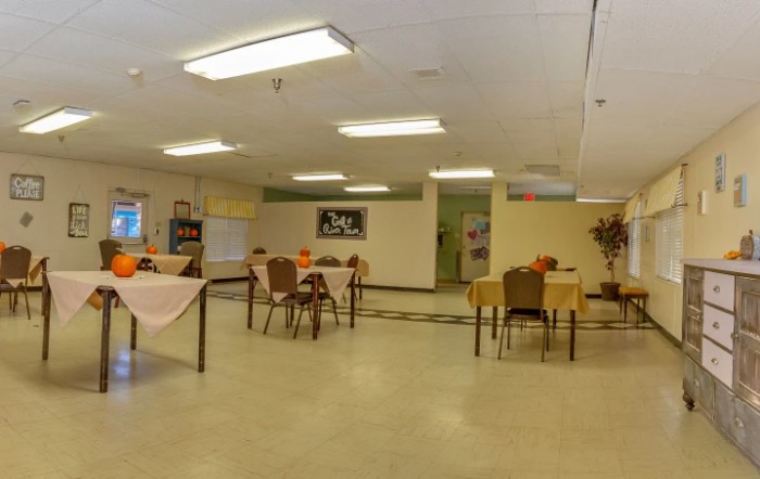 An empty dining hall with tables and chairs, decorated with small centerpieces.