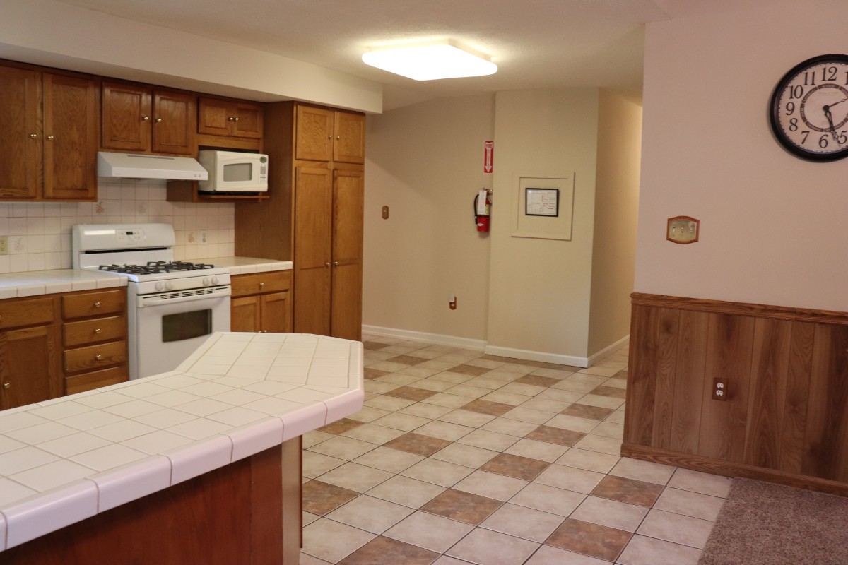 A kitchen interior with tiled flooring, wooden cabinets, a microwave, and an oven.
