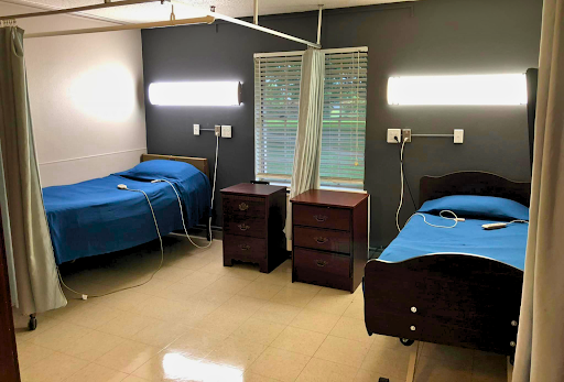 A view of a hospital patient room with two beds and bedside tables.