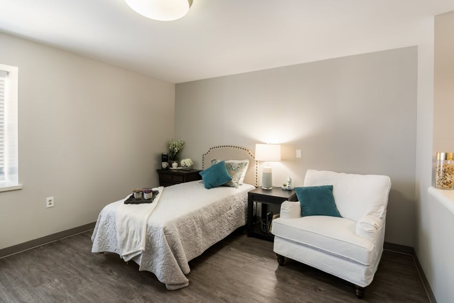 A cozy and elegantly designed bedroom with a single bed, comfortable chair, and stylish decor.