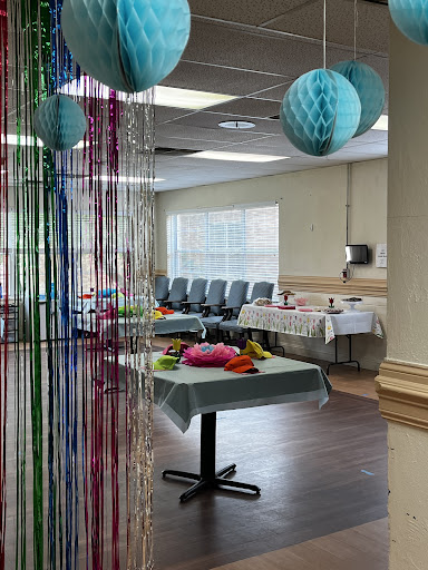 A vibrant and decorated indoor space set up for a celebration, featuring colorful decorations and tables laid out.