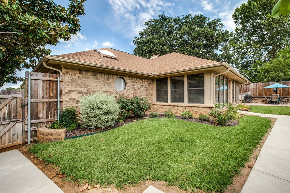 Suburban brick house with well-maintained landscaping and a green front yard.