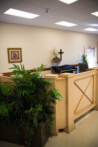 A serene interior space featuring decorative plants, artwork, and a piano.