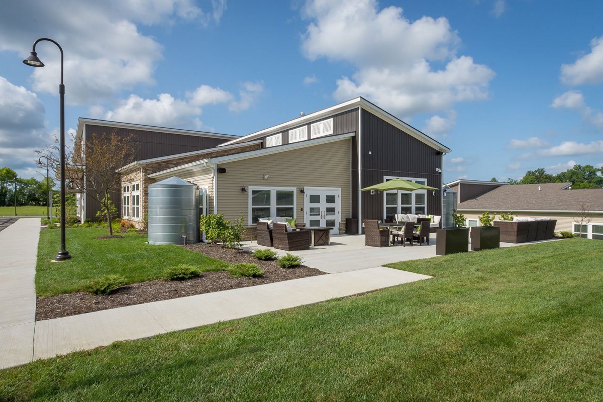 A modern house with a well-manicured lawn and outdoor patio area under a partly cloudy sky.