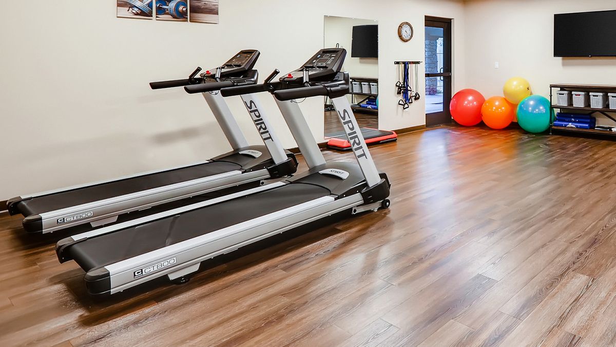 A clean and well-equipped gym with two treadmills and a wooden floor.