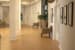 A hallway with wooden flooring, decorated with chairs and various wall decorations.