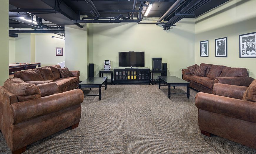 A cozy living room with brown sofas, a TV, and coffee tables on a carpeted floor.
