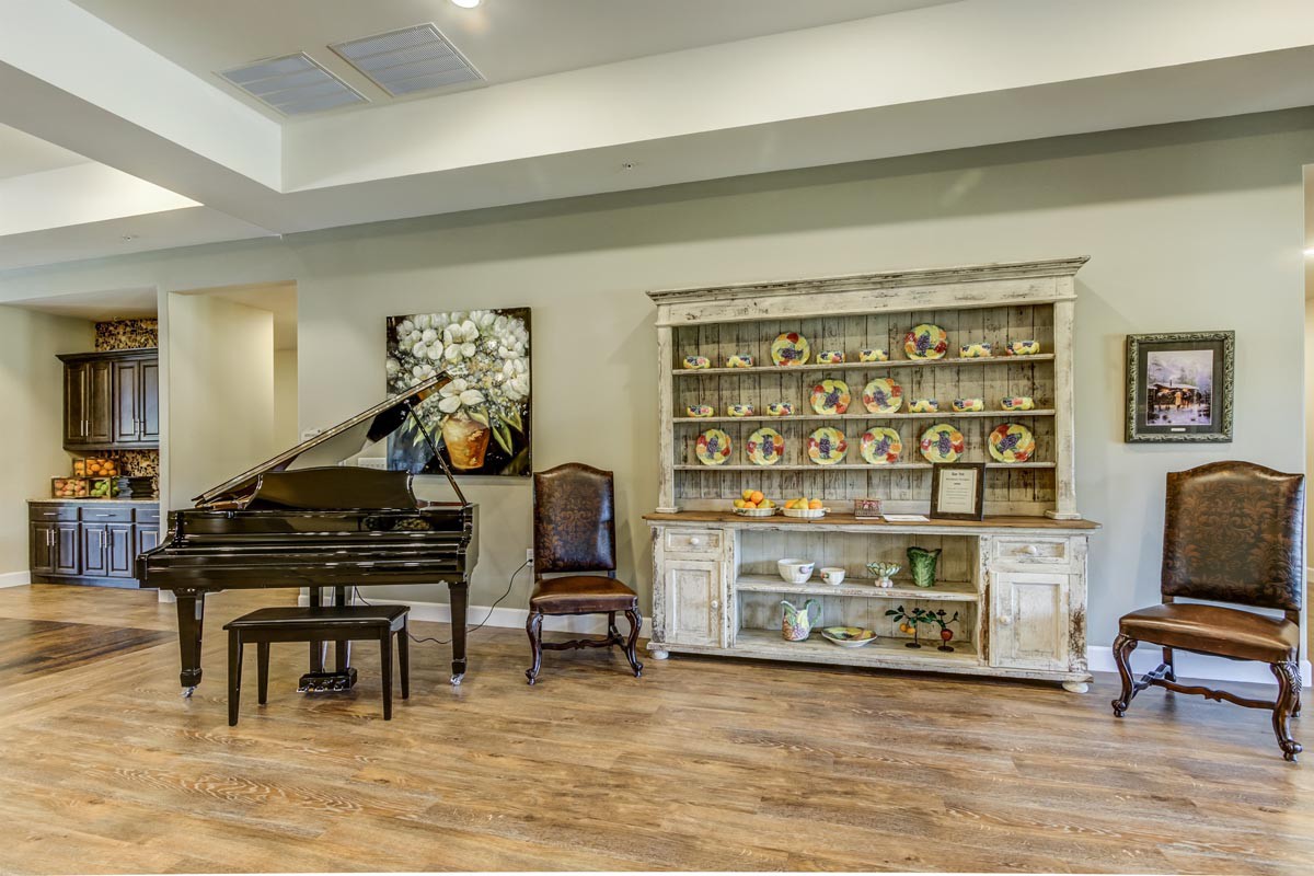 A cozy living room featuring a grand piano and a decorative shelf filled with ceramics.