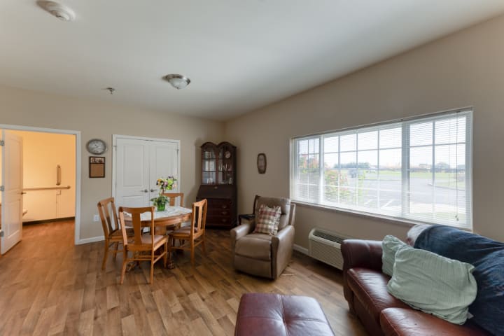 A cozy living room with a dining area, featuring wooden flooring and comfortable seating.