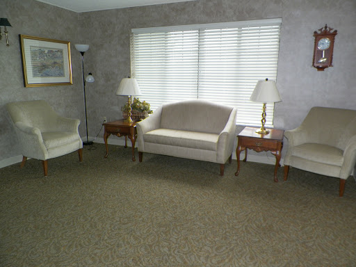 A simple and spacious living room featuring a sofa, two chairs, and side tables with lamps.