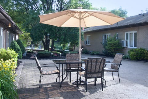 A sunny patio with outdoor furniture including a table, chairs, and a large umbrella.