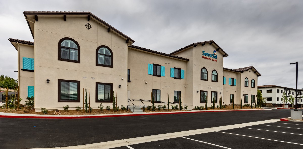 A modern hotel building with a parking area under a cloudy sky.