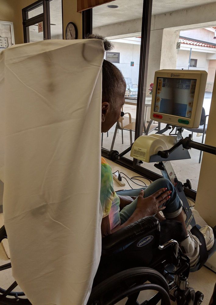 A patient seated in a hospital setting, engaging with medical equipment and a monitor.