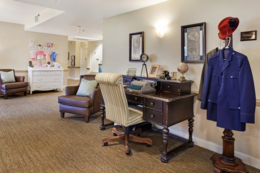 A cozy home office with a vintage wooden desk, an upholstered chair, and warm lighting.