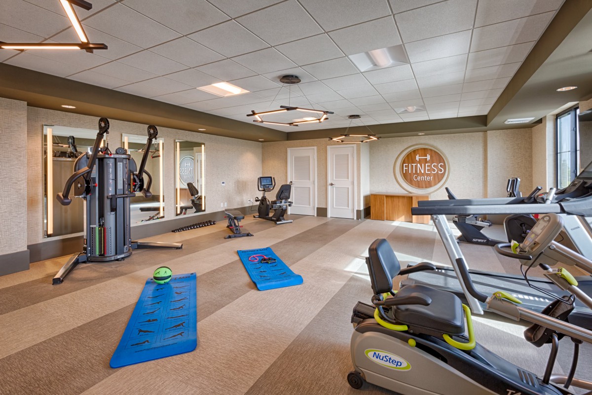 A well-equipped gym with various exercise machines and yoga mats.