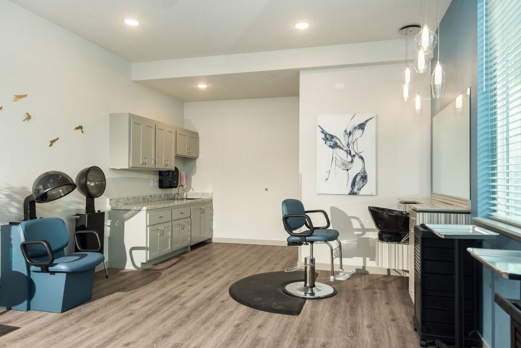 A modern salon interior with a styling chair, hairdryer, mirror, and artwork displayed on the wall.