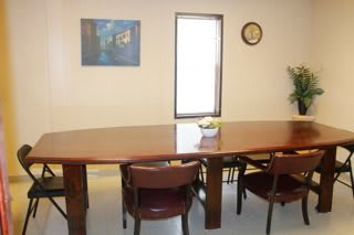 A conference room with a large table, several chairs, artwork on the wall, and a clock.