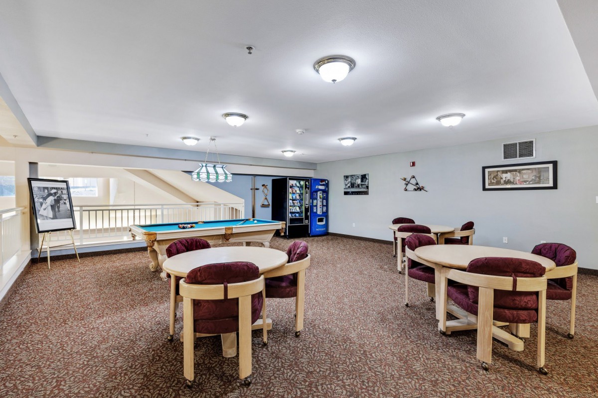 A spacious lounge area with tables, chairs, vending machines, and a pool table.