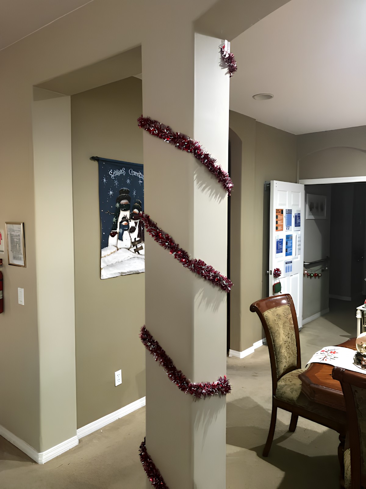 A warmly decorated dining area with a column wrapped in tinsel, creating a festive atmosphere.