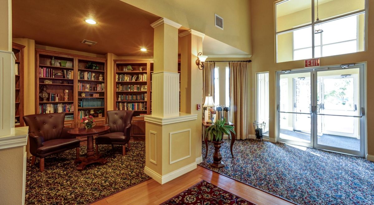 A cozy living room with a traditional library and warm lighting.