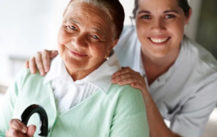 An elderly woman with her caregiver smiling together.