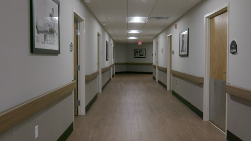 A quiet hallway in a hospital, featuring closed doors and framed pictures on the walls.