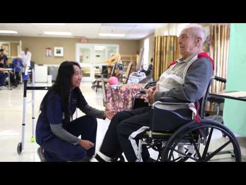 A caregiver assists a senior in a wheelchair during a rehabilitation session.