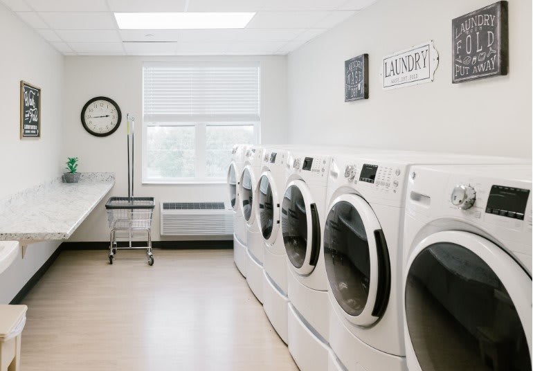 A modern and clean laundry room with multiple washing machines.