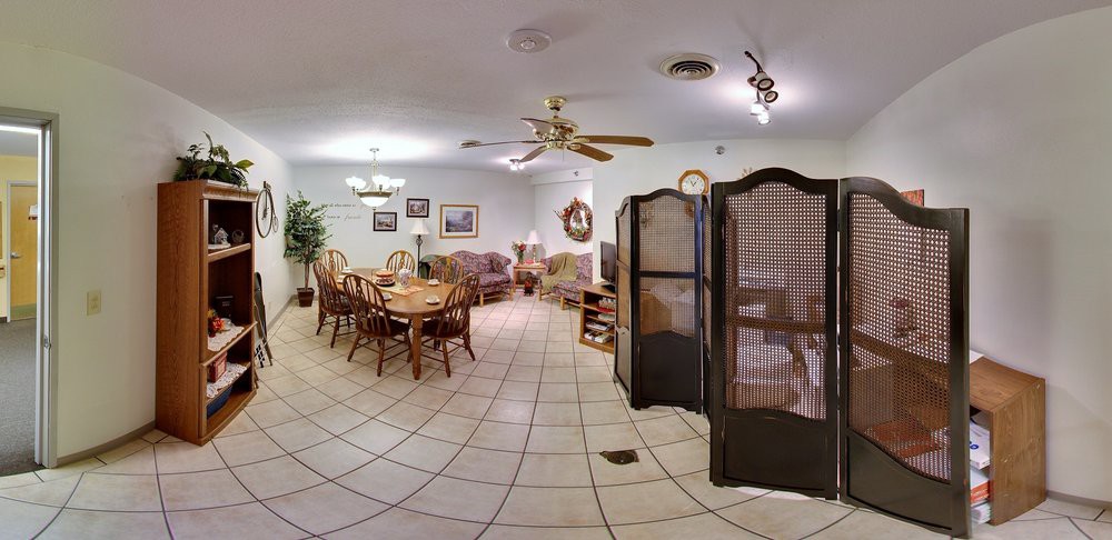 A spacious living and dining area featuring wooden furniture, tile flooring, a ceiling fan, and decorative elements.