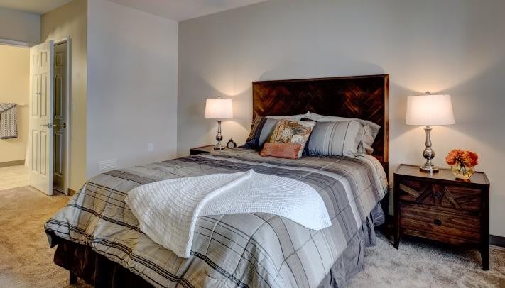A cozy bedroom with a comfortable bed, side lamp, and stylish bedding.