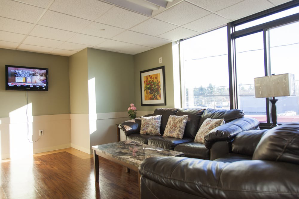 A cozy living room with a comfortable sofa and a coffee table, illuminated by natural light streaming through large windows.