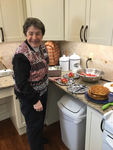 A woman happily preparing a meal in a cozy kitchen, surrounded by delicious food.