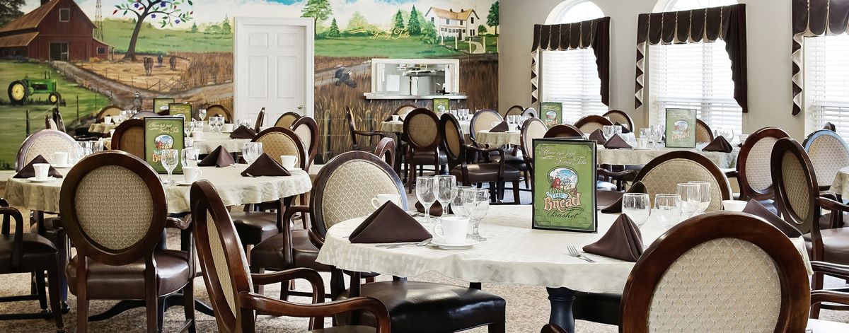 An elegant dining area with neatly set tables, featuring a scenic mural on the wall.