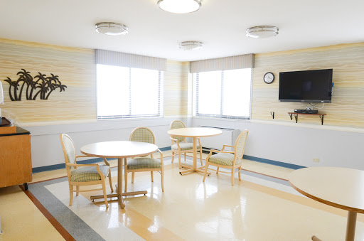 A bright and spacious waiting area in a hospital with tables and chairs.