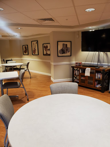 A cozy dining area featuring tables and chairs, decorated with artwork and complemented by a television.