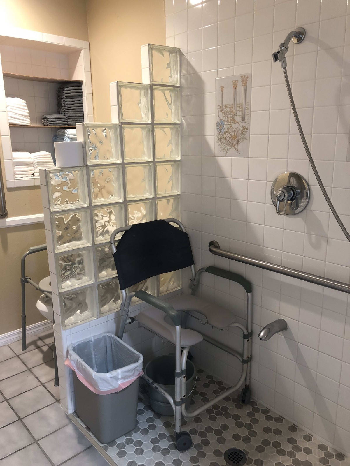An accessible bathroom featuring a shower with a chair and handrails.
