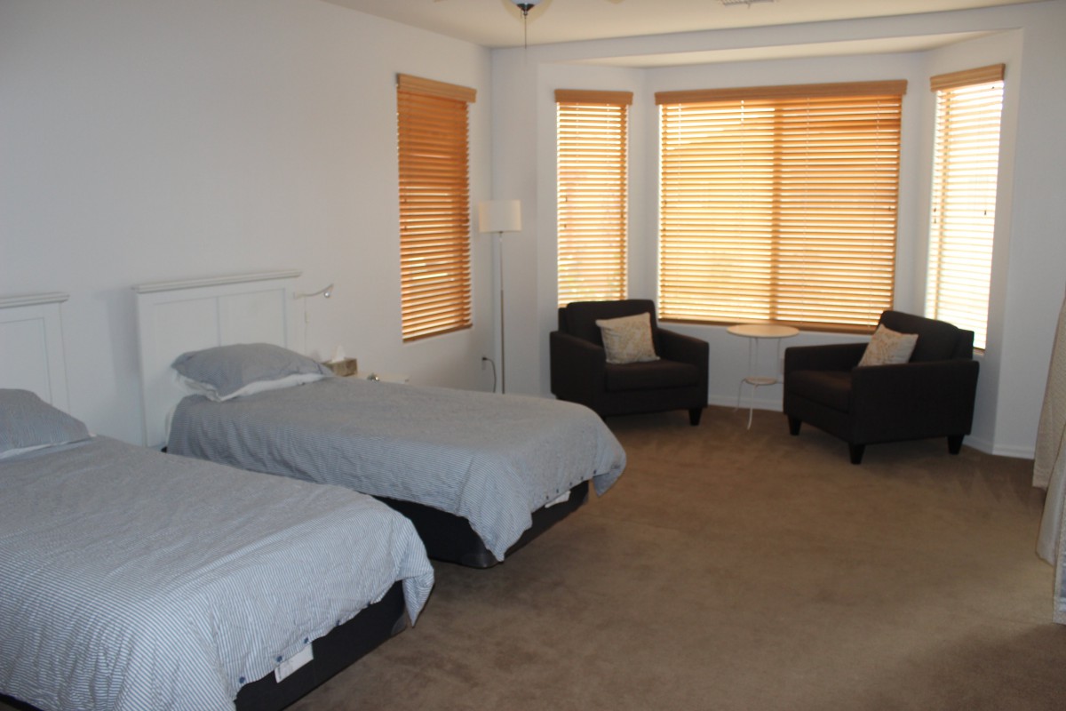 A cozy bedroom with two twin beds and a seating area by the window.