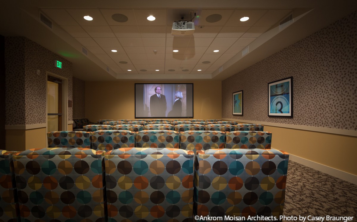 A cozy theater room with patterned chairs and a large screen.