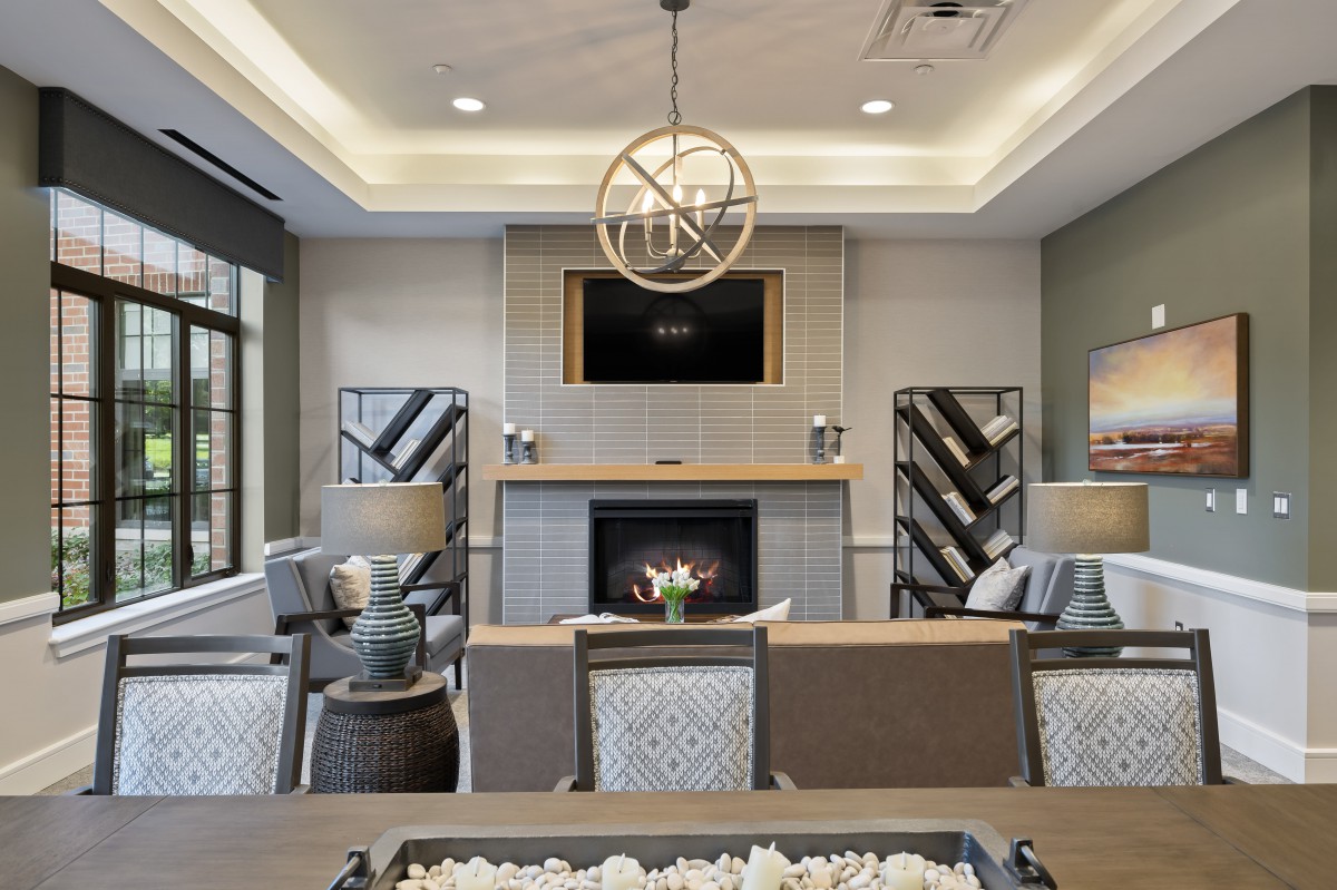 A modern living room featuring a cozy fireplace, elegant chandelier, and stylish furniture.