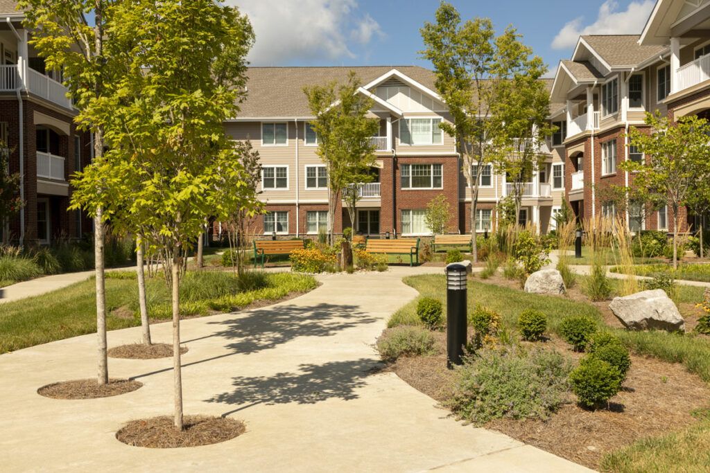 A modern residential apartment complex with landscaped grounds and a winding pathway.